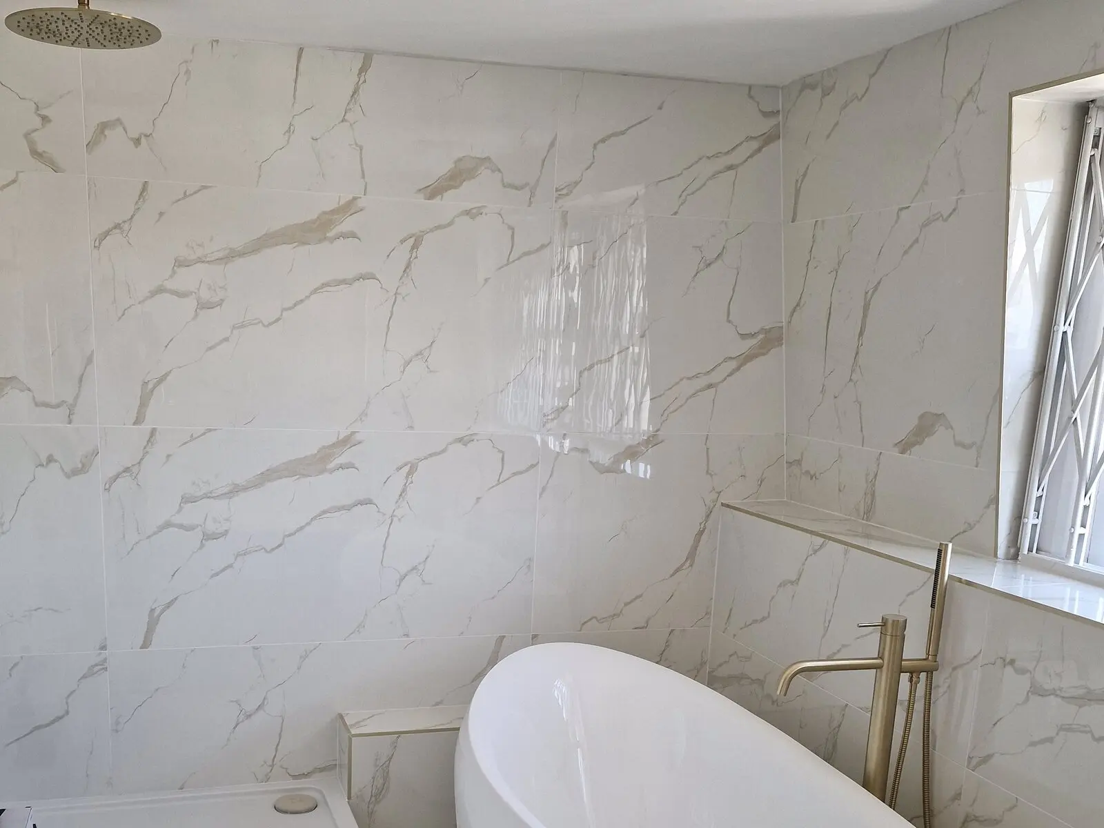 Marble effect bathroom with a freestanding bath, walk in shower and brass fittings