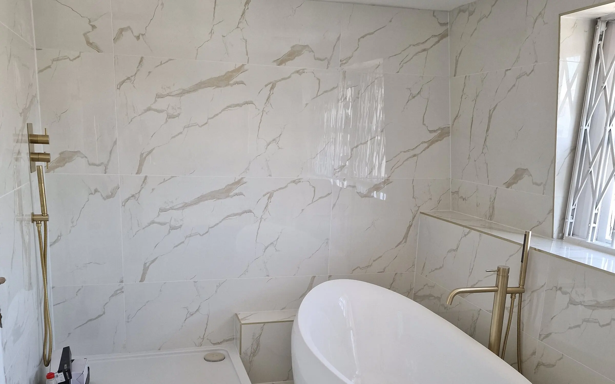 Completed bathroom renovation with a freestanding bath, walk in shower and brass fittings